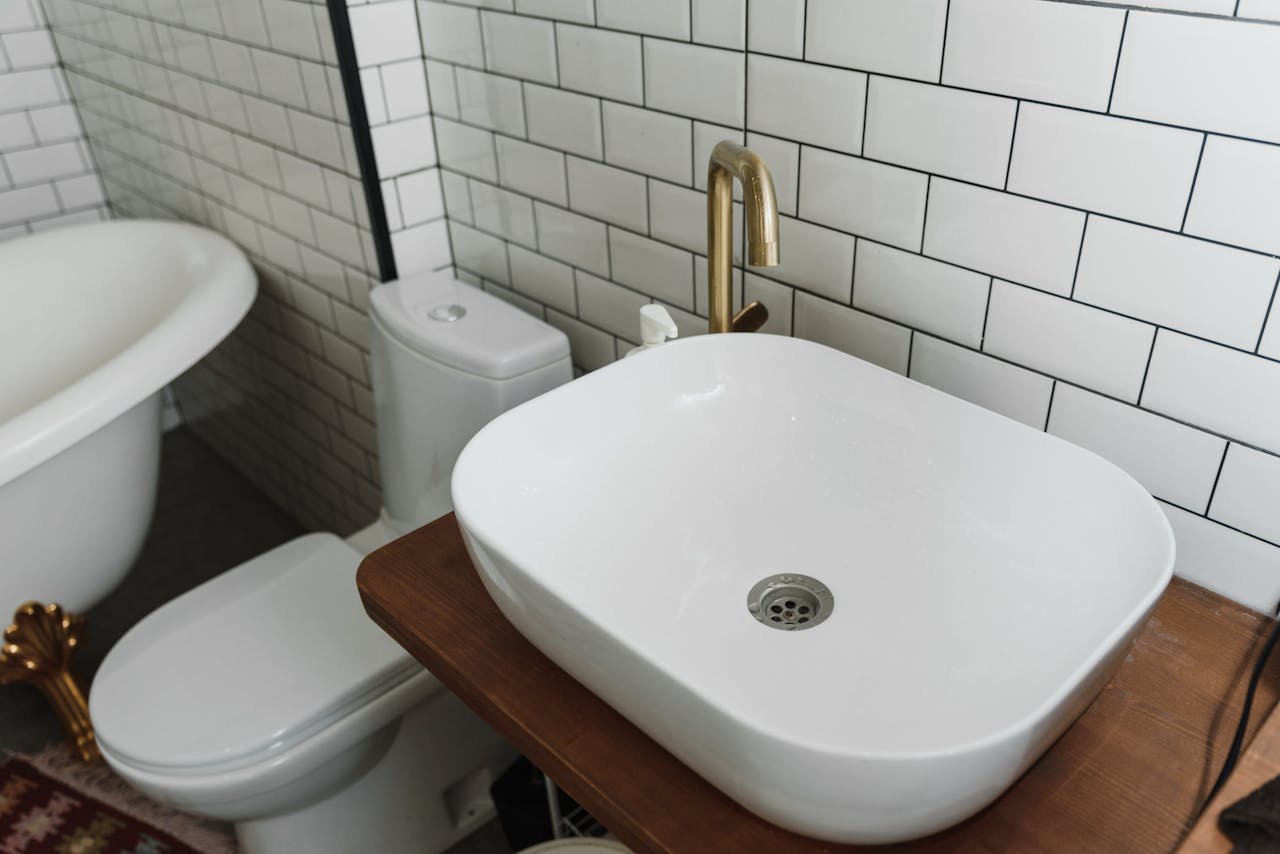 A Bathroom with White Theme with a Gold Faucet